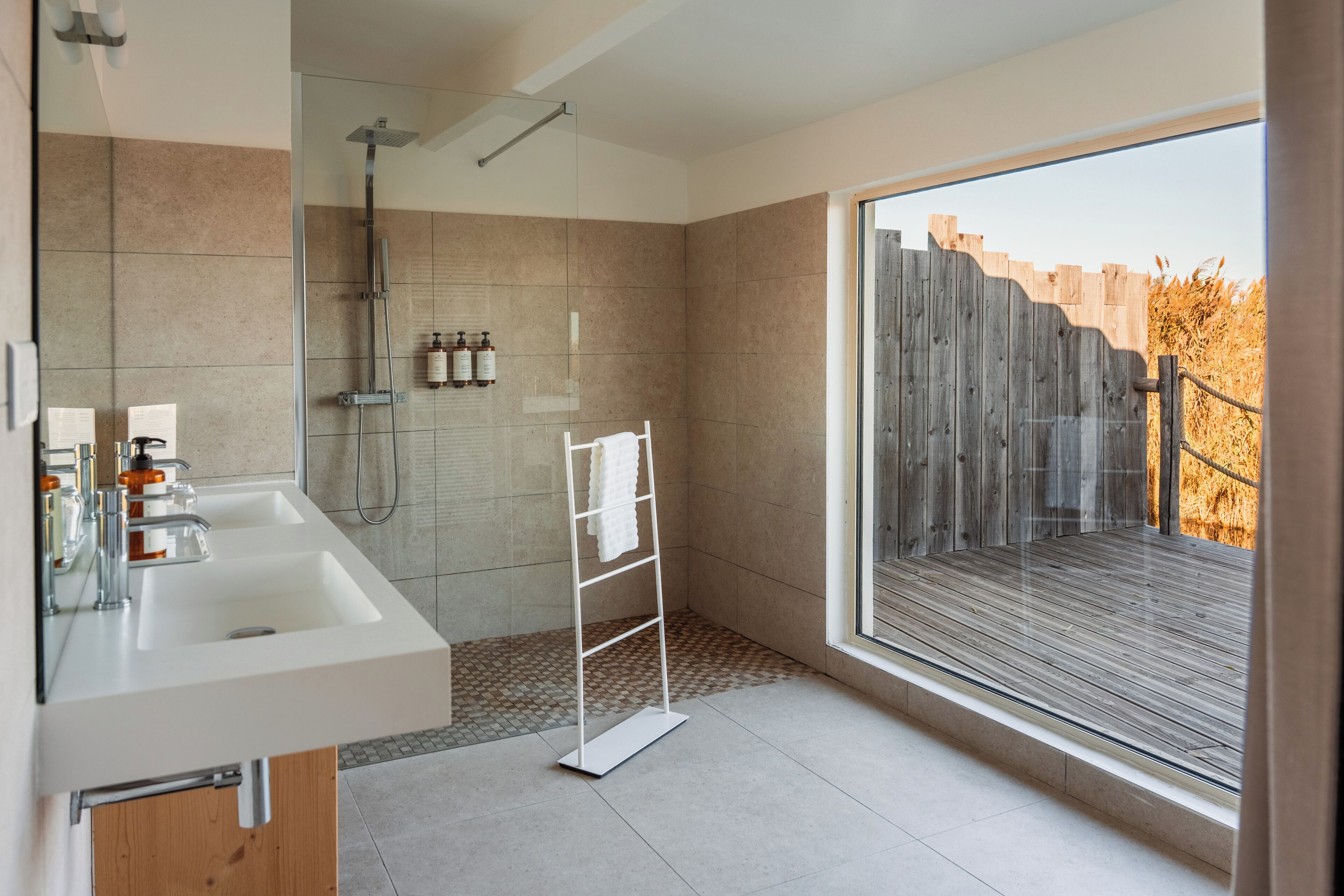 Une salle de bain moderne avec une douche, deux lavabos et une grande fenêtre.