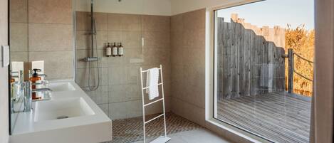 Une salle de bain moderne avec une douche, deux lavabos et une grande fenêtre.