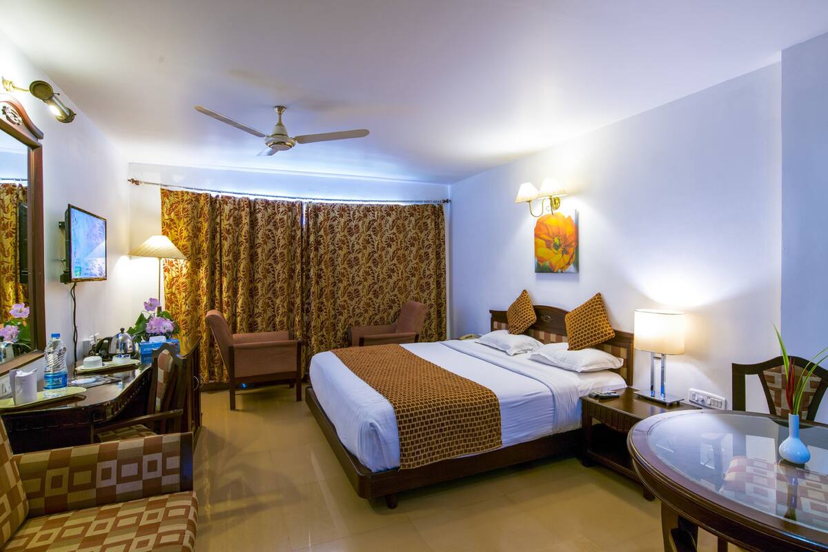 A hotel room with a bed, desk, chairs, and a dining table.