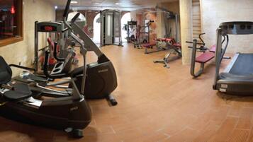 Un gimnasio con máquinas de cardio, equipo de pesas y una cinta de correr.