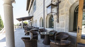 An outdoor patio area with wicker furniture and stone columns. - Hotel SPA Abadía de Los Templarios (La Alberca)