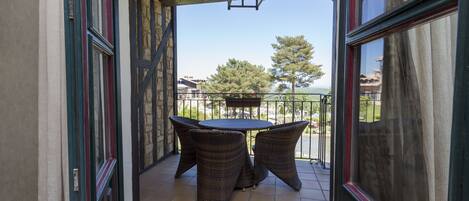 Ein Balkon mit Tisch und Stühlen, Blick auf die Landschaft und eine Steinmauer.