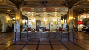 A lobby with a central reception desk, stone walls, and a tiled floor. - Hotel SPA Abadía de Los Templarios (La Alberca)