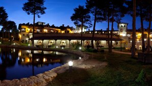 A large, illuminated building with multiple levels and arched windows, surrounded by trees and a pond. - Hotel SPA Abadía de Los Templarios (La Alberca)