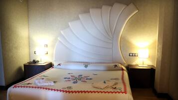 A hotel room with a large bed, two bedside tables with lamps, and a decorative headboard.