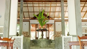 A staircase leading to a covered area with a central fountain, surrounded by wooden chairs and a patterned wall. - Villa Birdlake (Hikkaduwa)