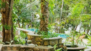 A stone staircase leading up to a pool area surrounded by lush greenery and trees. - Villa Birdlake (Hikkaduwa)