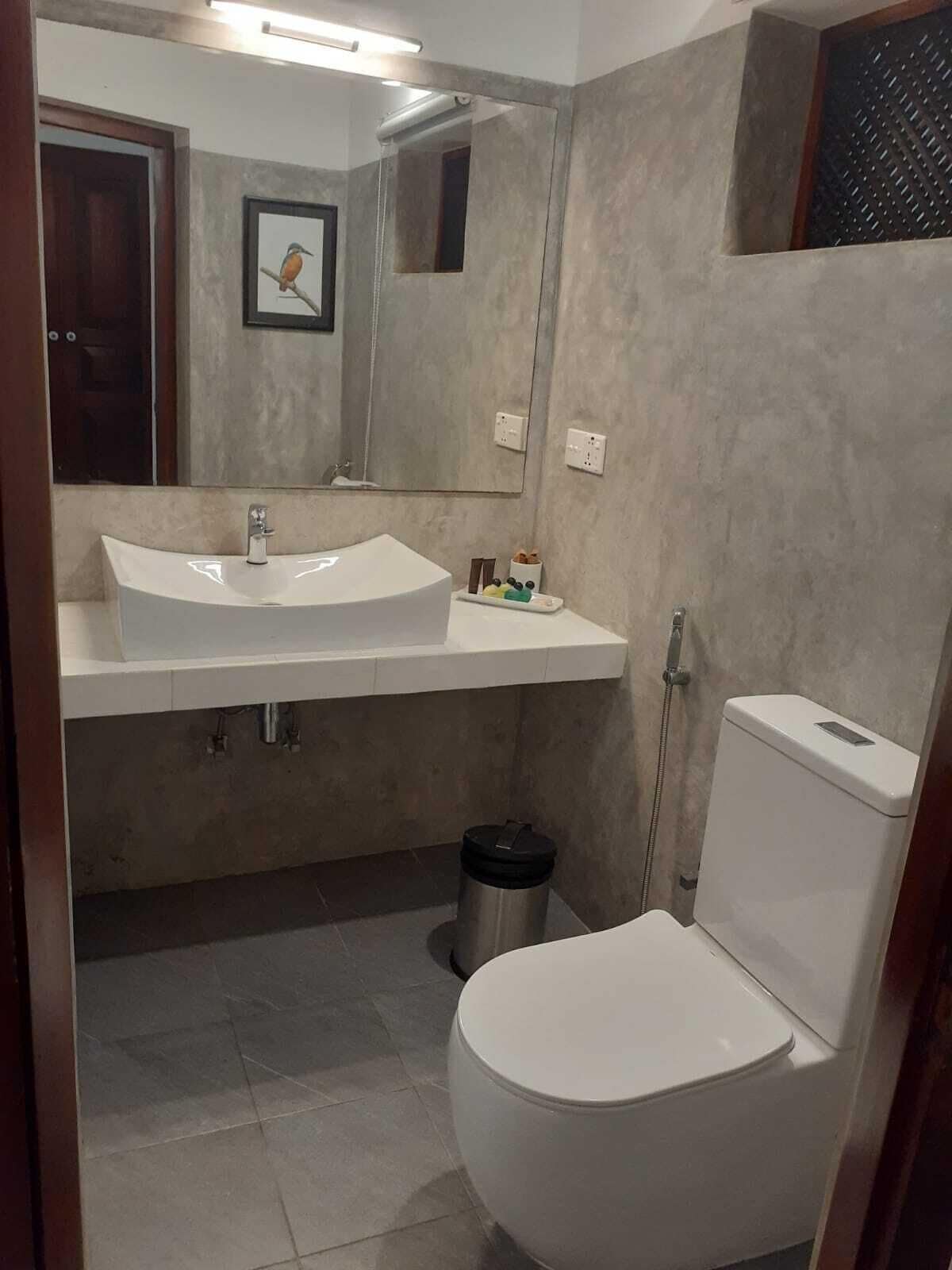 A bathroom with a white sink, mirror, and toilet.