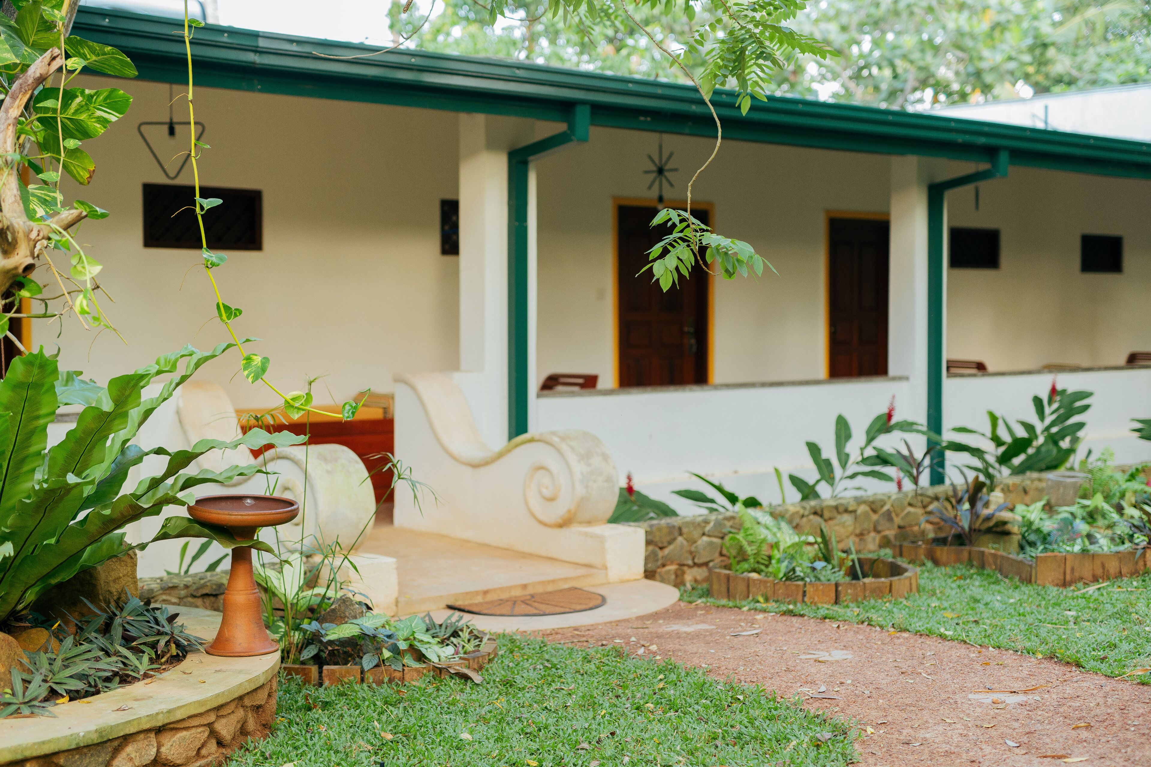 A garden with a stone wall, a white bench, and a rustic outdoor seating area.