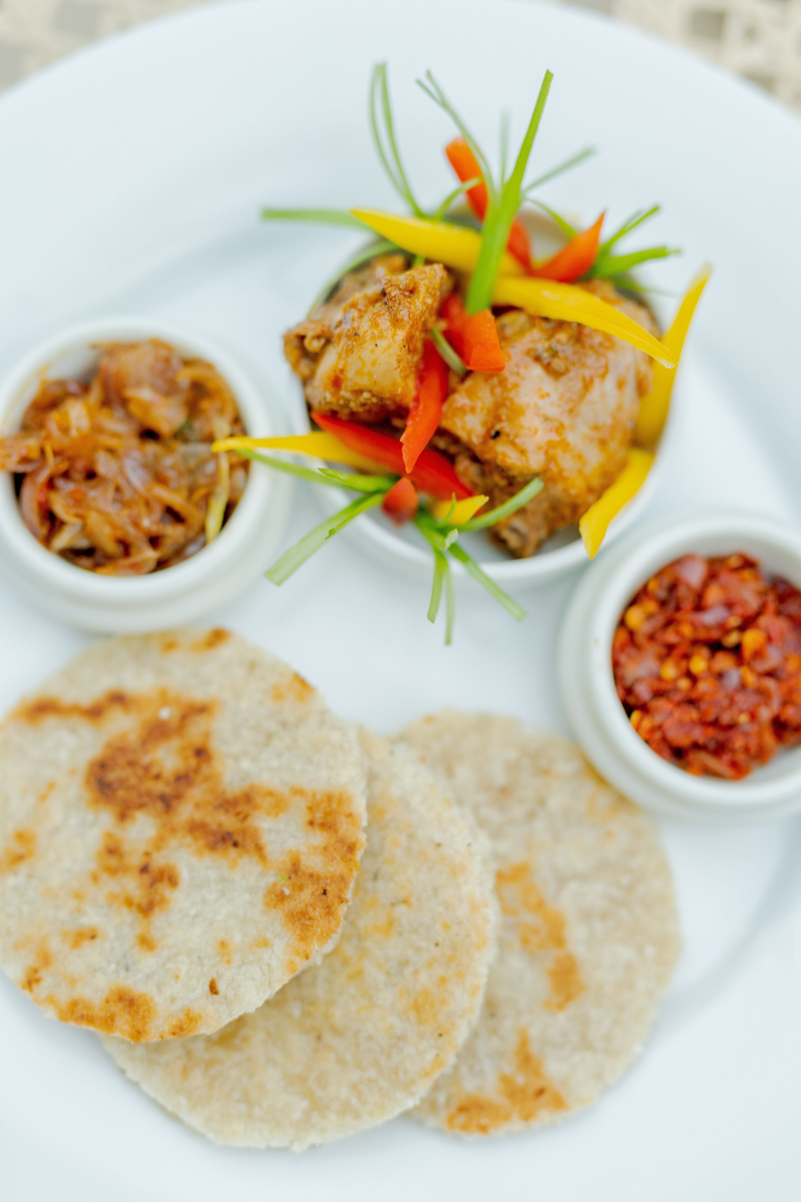 Une assiette composée de poulet grillé, de légumes et de pains plats.