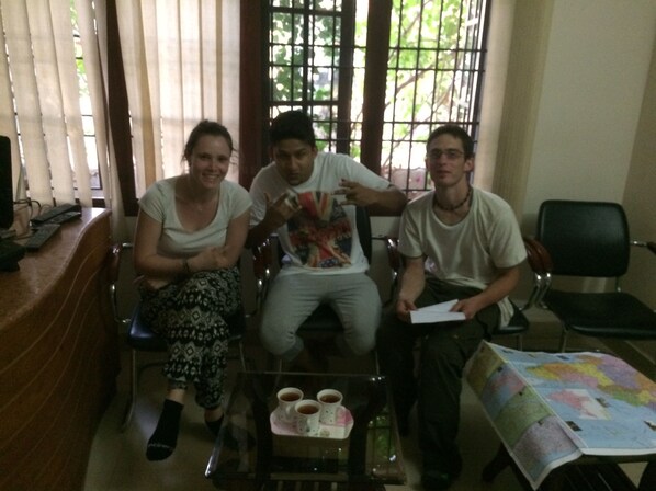 A room with three people seated, a table with cups, and a chair with a map.