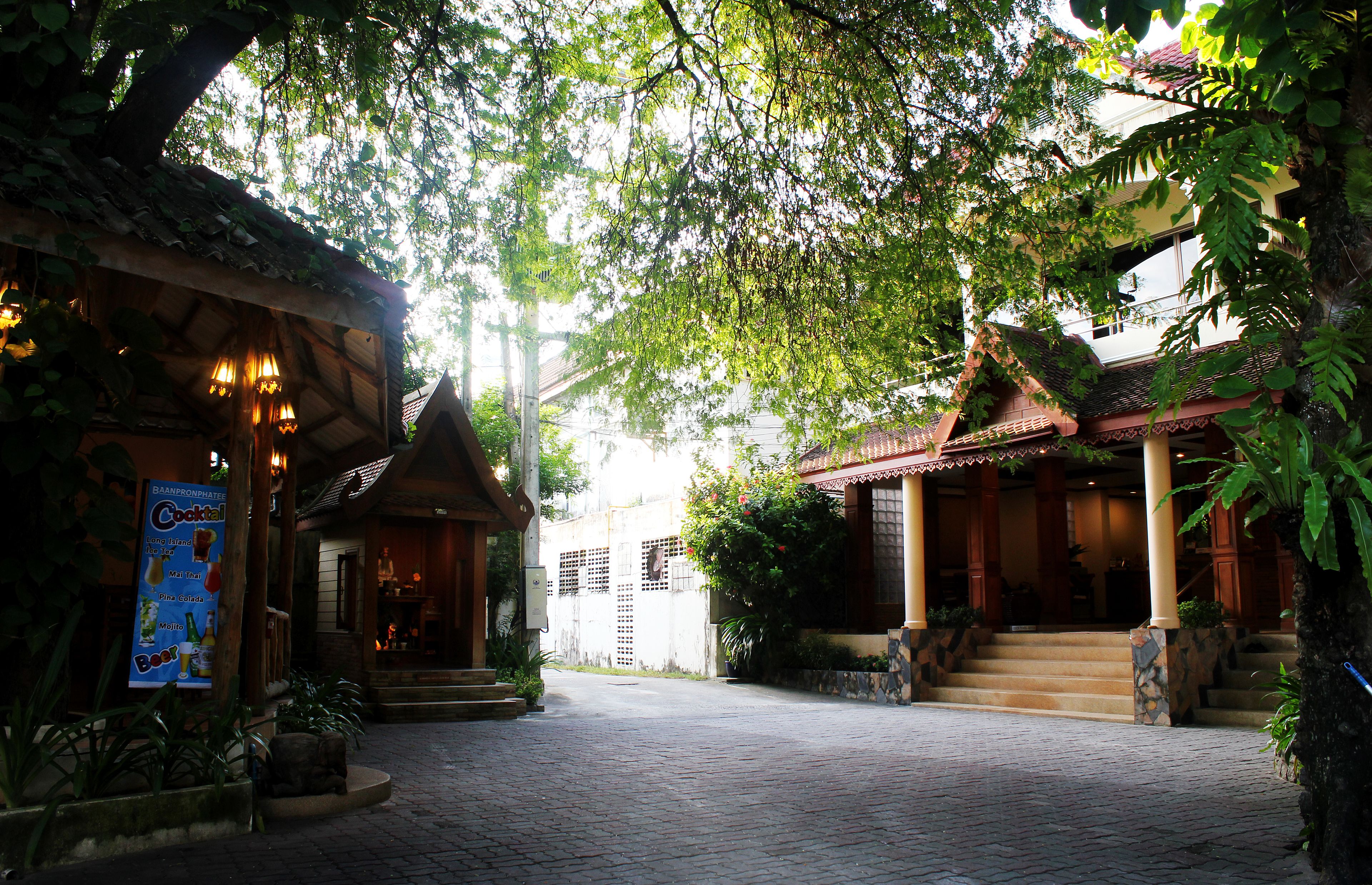 A courtyard with a traditional building, a covered seating area, and a staircase leading to a second floor.