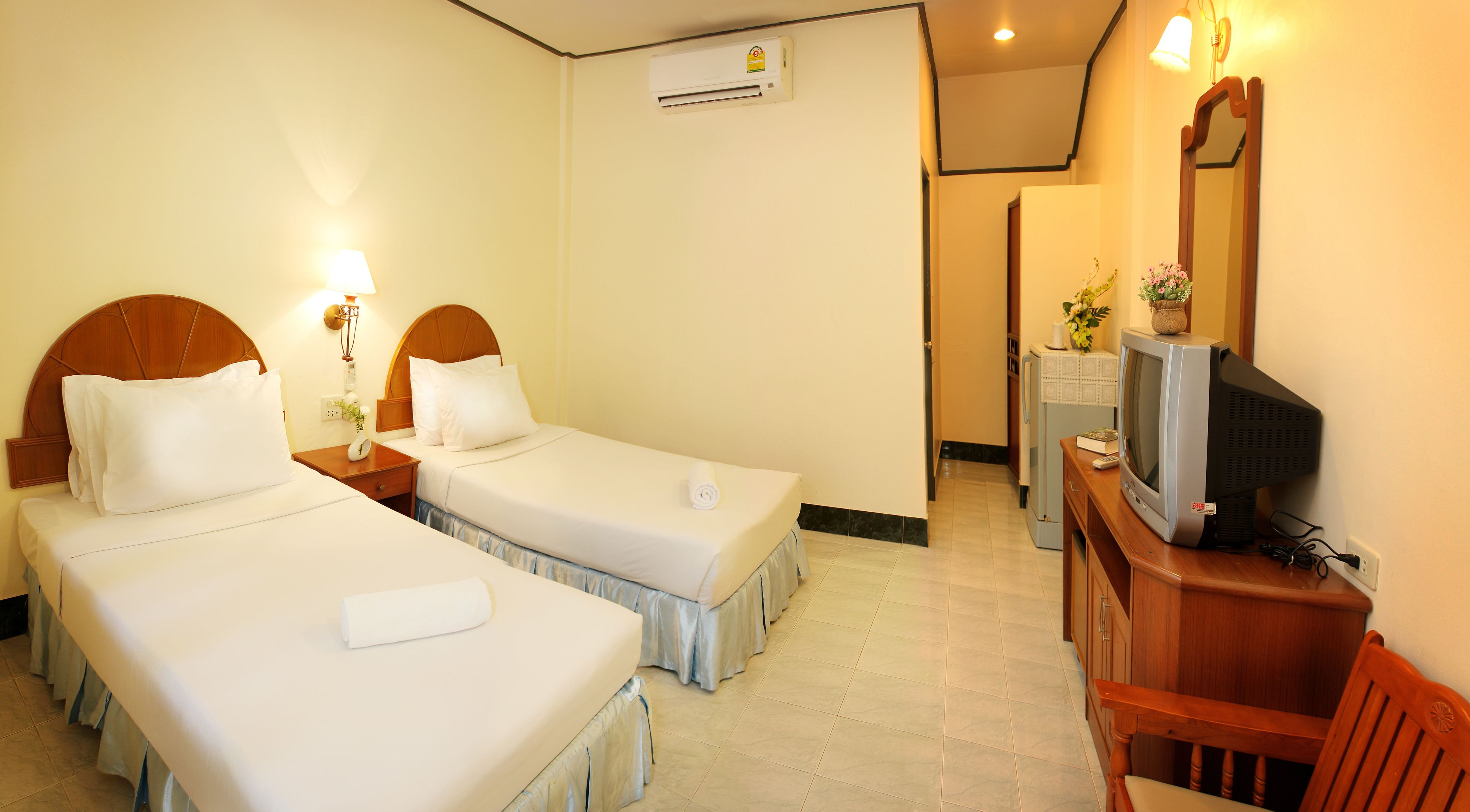 Une chambre d’hôtel avec deux lits simples, une télévision, un bureau et une chaise.