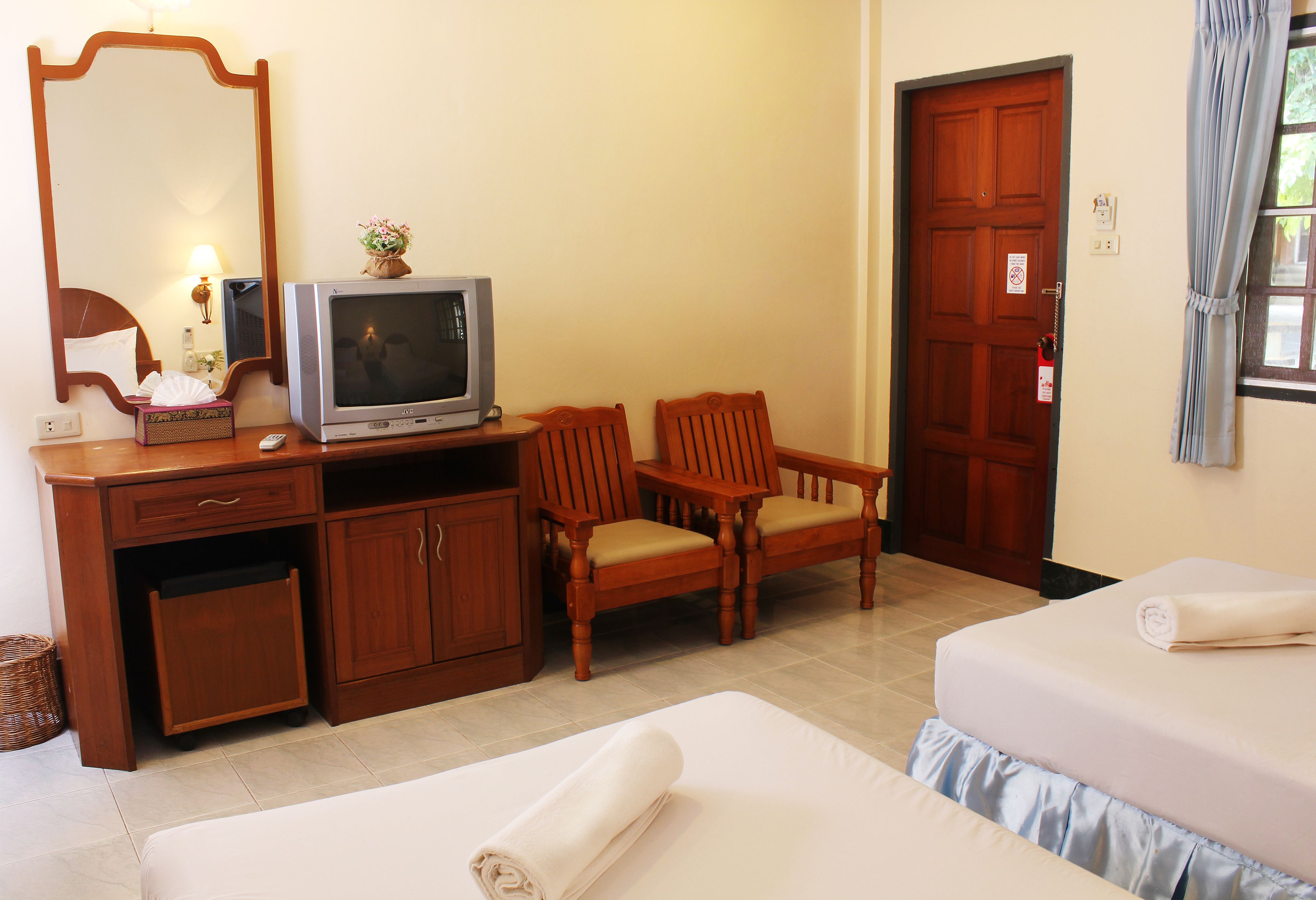 Una habitación de hotel con cama, escritorio, televisor, silla y puerta de madera.