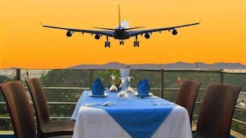A table set for dining with a view of an airplane landing.