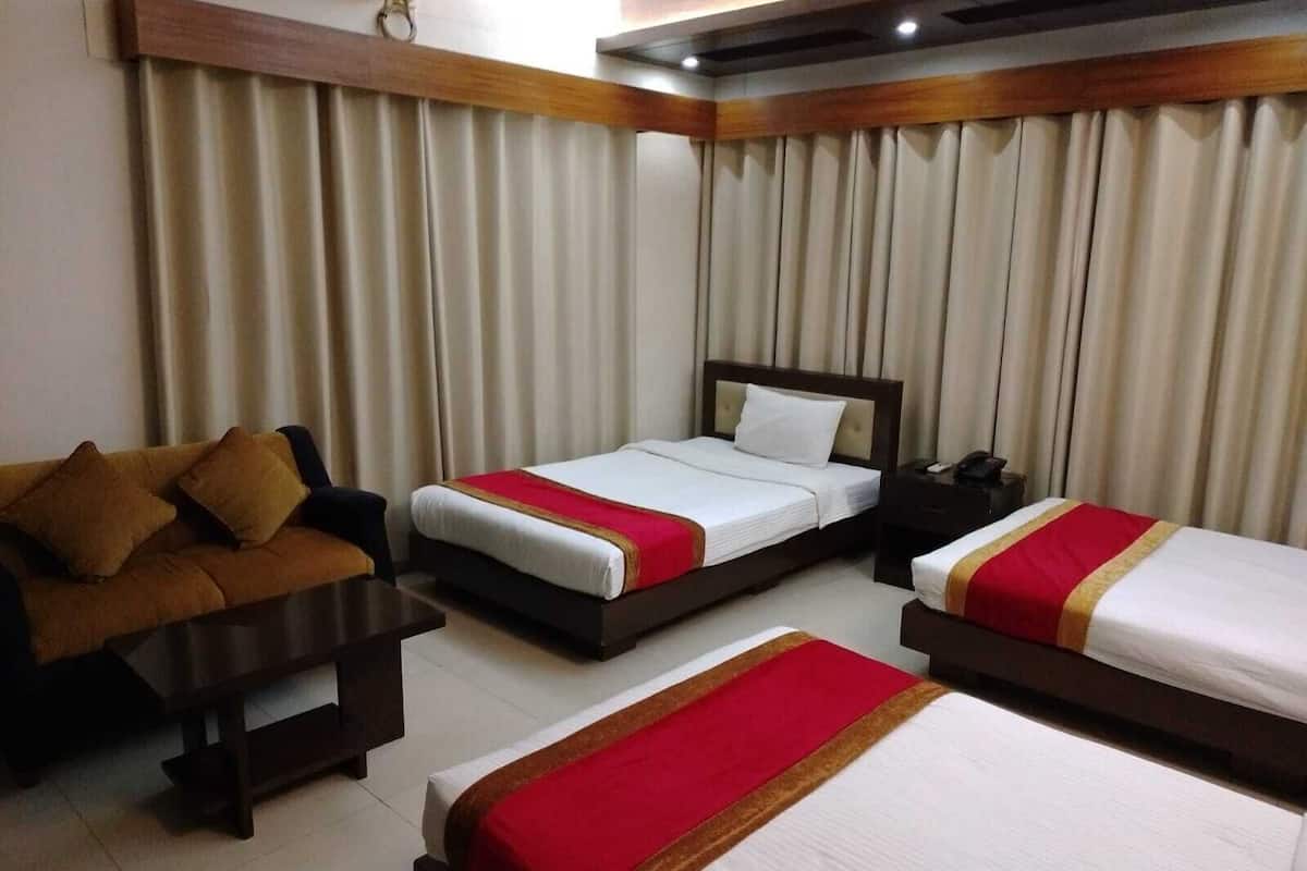 A hotel room with two beds, a sofa, a bedside table, and curtains.