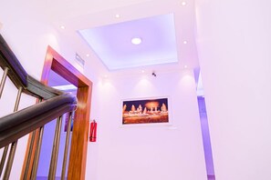 A staircase with a handrail, a ceiling with recessed lighting, and a framed picture on the wall. - Air Inn (Dhaka)
