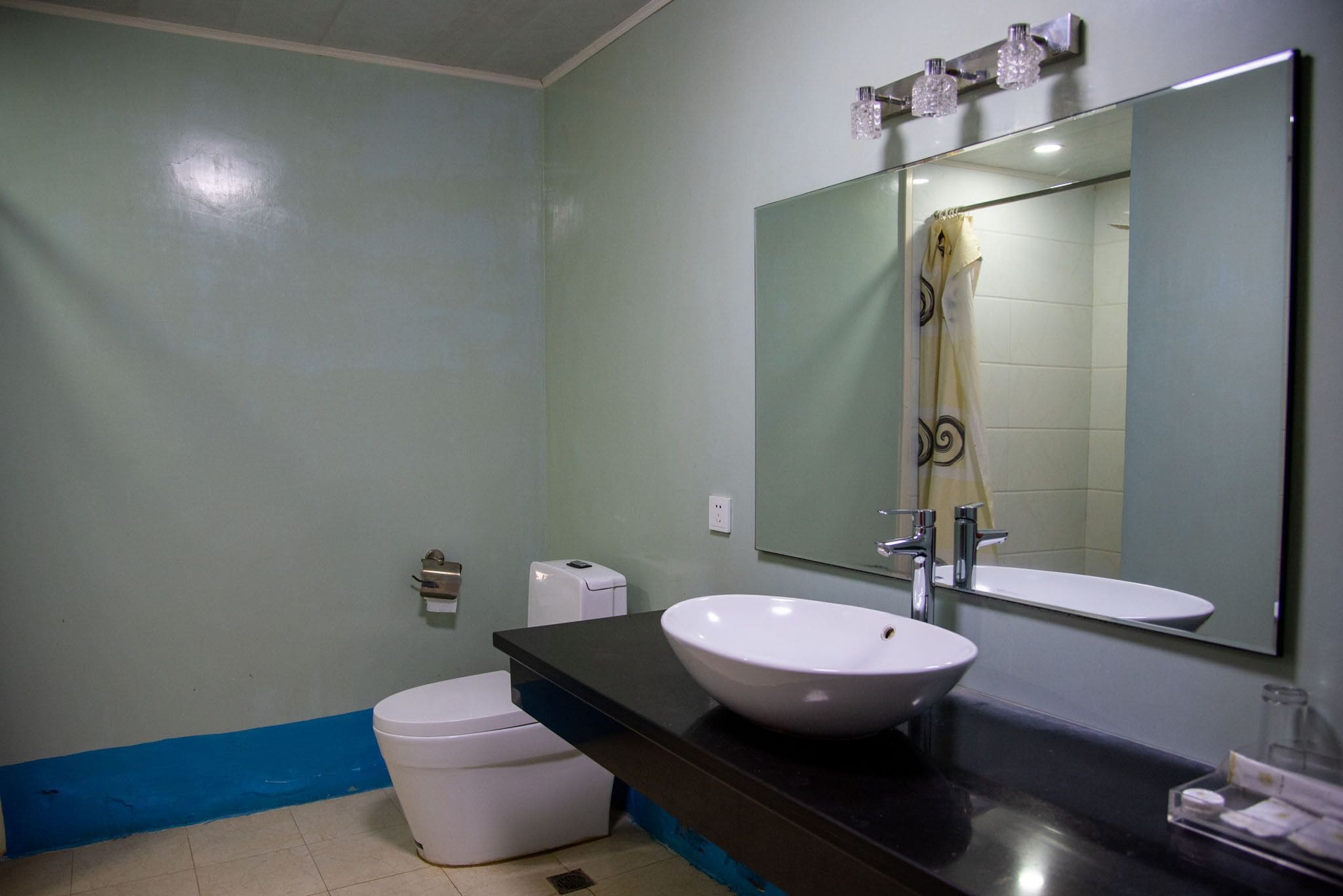 Un baño con un lavabo blanco, un espejo grande y una cortina de ducha.
