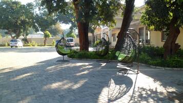 A paved outdoor area with hanging chairs and trees.
