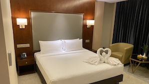 A hotel room with a large bed, a bedside table with a phone, a chair, and a small table with a plant. - Hotel Tower Inn (Chittagong)