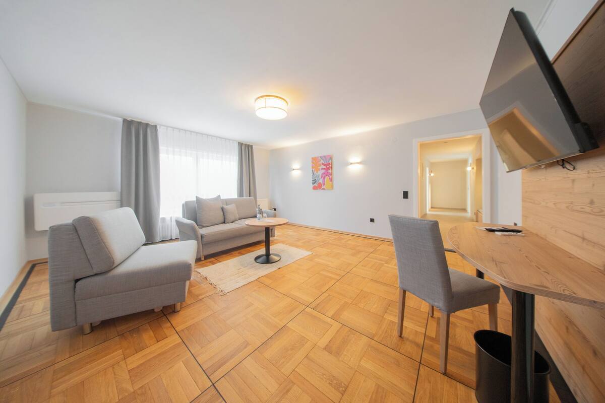 A modern living room with a sofa, a round coffee table, and a dining area with a table and chairs.