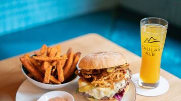 Un plato con una hamburguesa, papas fritas y una cerveza en una mesa de madera.