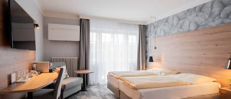 Una habitación de hotel moderna con una cama, un escritorio, una silla, una mesita y un televisor.