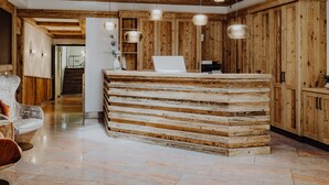 Un espace d’accueil avec un comptoir en bois, des luminaires suspendus et un escalier en arrière-plan.