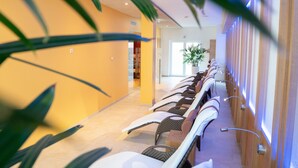 Un couloir d’hôtel avec des rangées de coins salon, une plante en pot et un mur en bois.