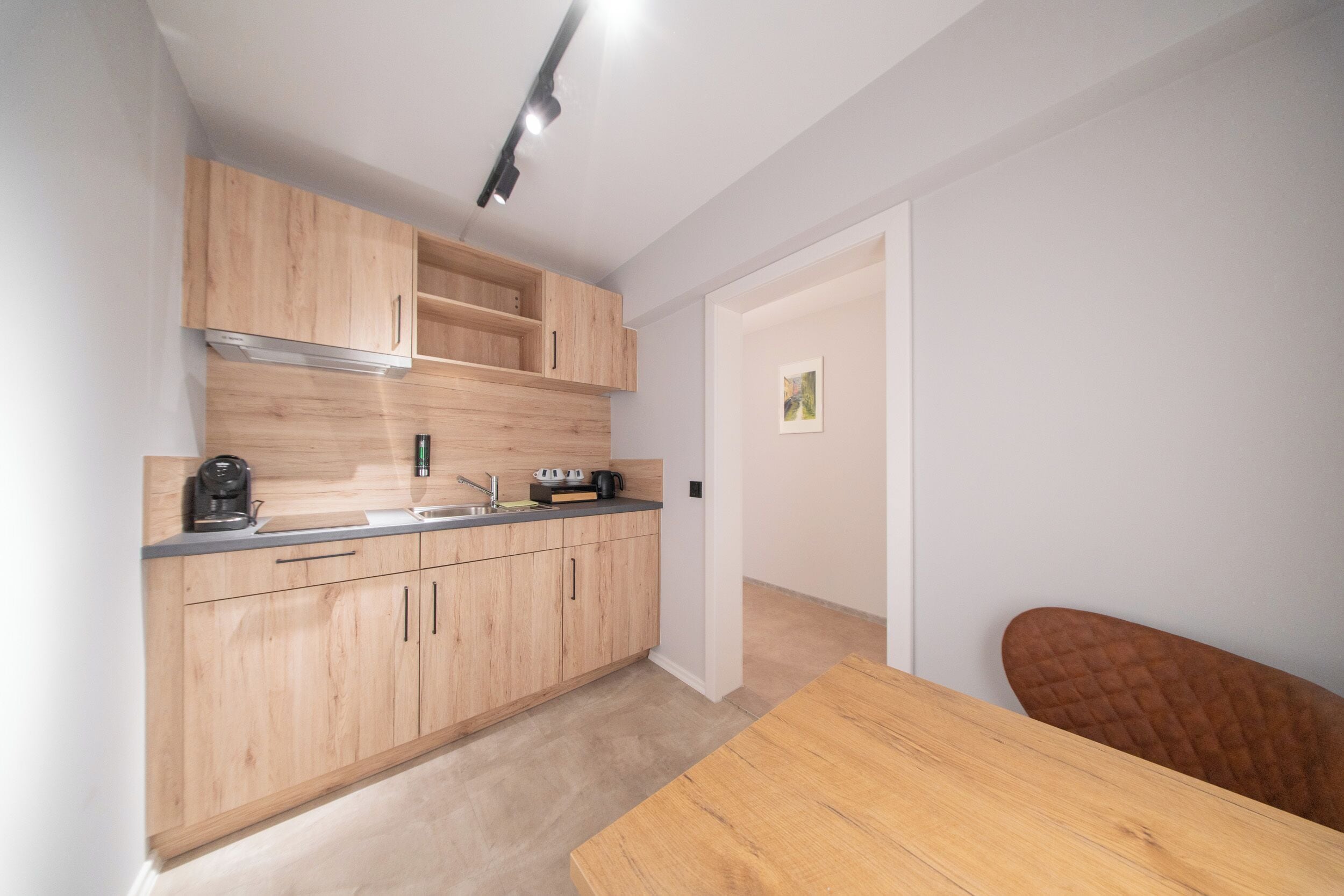 A modern kitchen with wooden cabinets, a countertop, and a dining table.