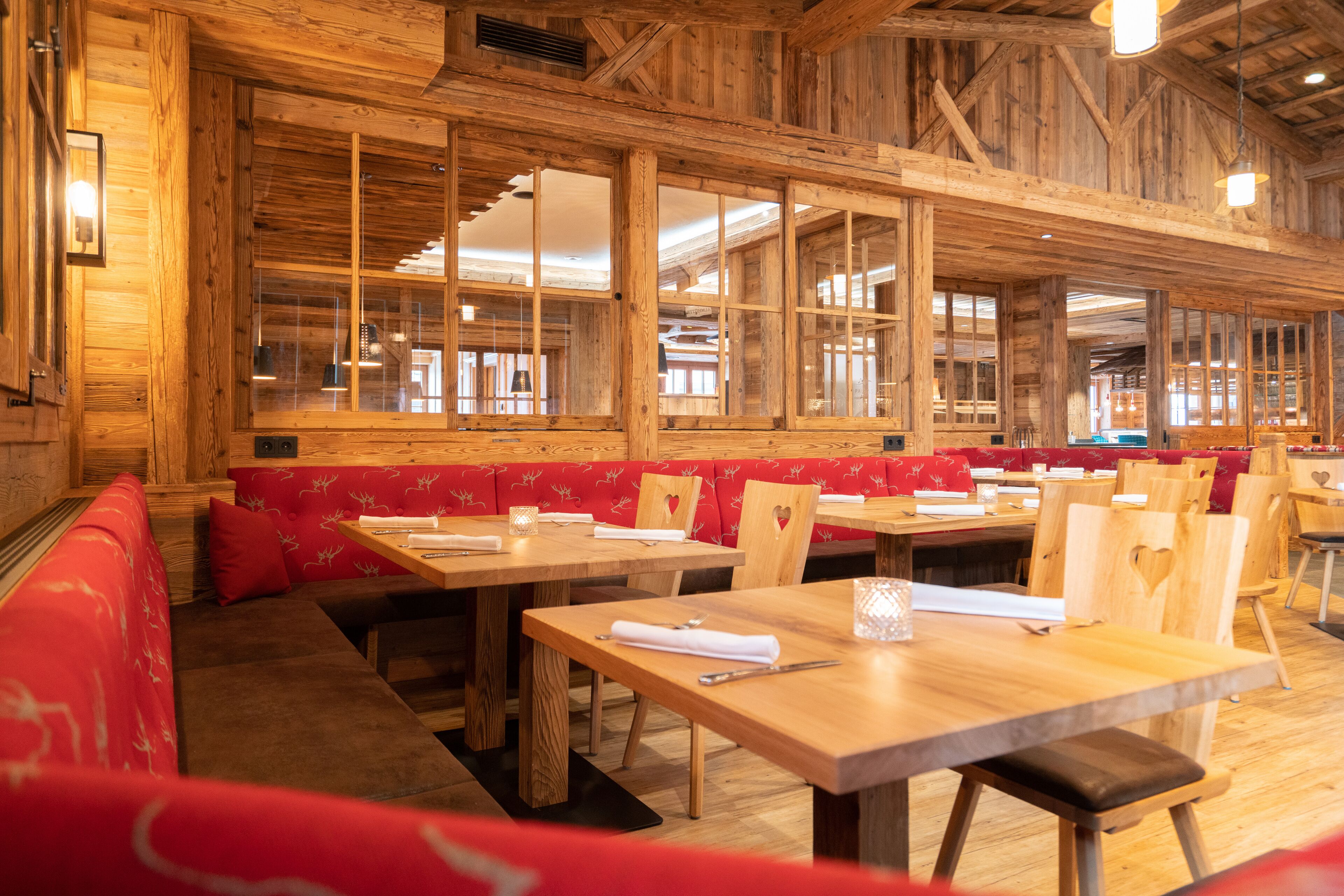 Un intérieur en bois, avec des sièges rembourrés de couleur rouge et des tables en bois.