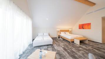 A modern hotel room with a large bed, a smaller bed, a desk with a chair, and a painting on the wall.