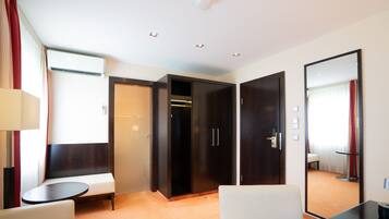 Ein Hotelzimmer mit Sitzecke, Kleiderschrank, Spiegel und einem kleinen Tisch.