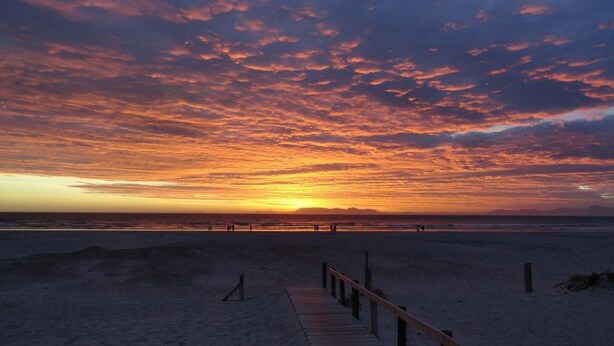 A beach with a wooden walkway leading to the water. - Melite Rooms (Cape Town)