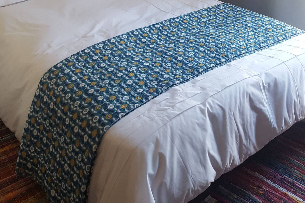 A hotel room with a bed, a curtain, and a plain wall.