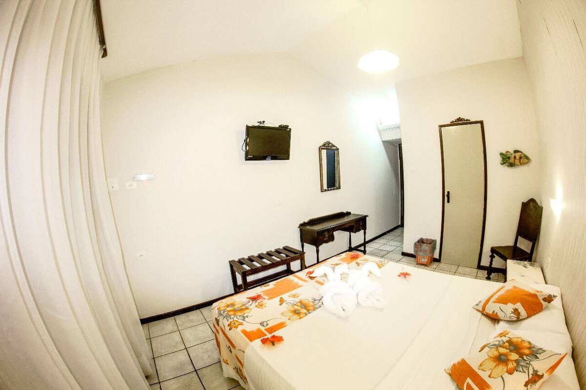 Habitación de hotel con cama, escritorio, espejo y armario.