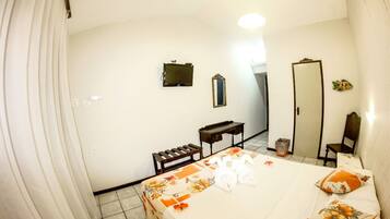 Habitación de hotel con cama, escritorio, espejo y armario.