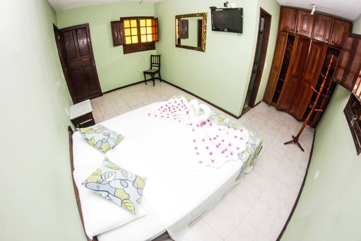 Un dormitorio con cama, una silla, un armario y una televisión.
