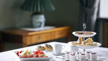 Preparación para el desayuno con pasteles, una bandeja de fruta y batidos sobre una mesa.