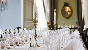 Una mesa de comedor formal adornada con varias copas de vino, un candelabro dorado y una araña.
