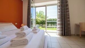A hotel room with a bed, a bathroom, and a view of greenery outside. - Residence Solidago (Pisa)