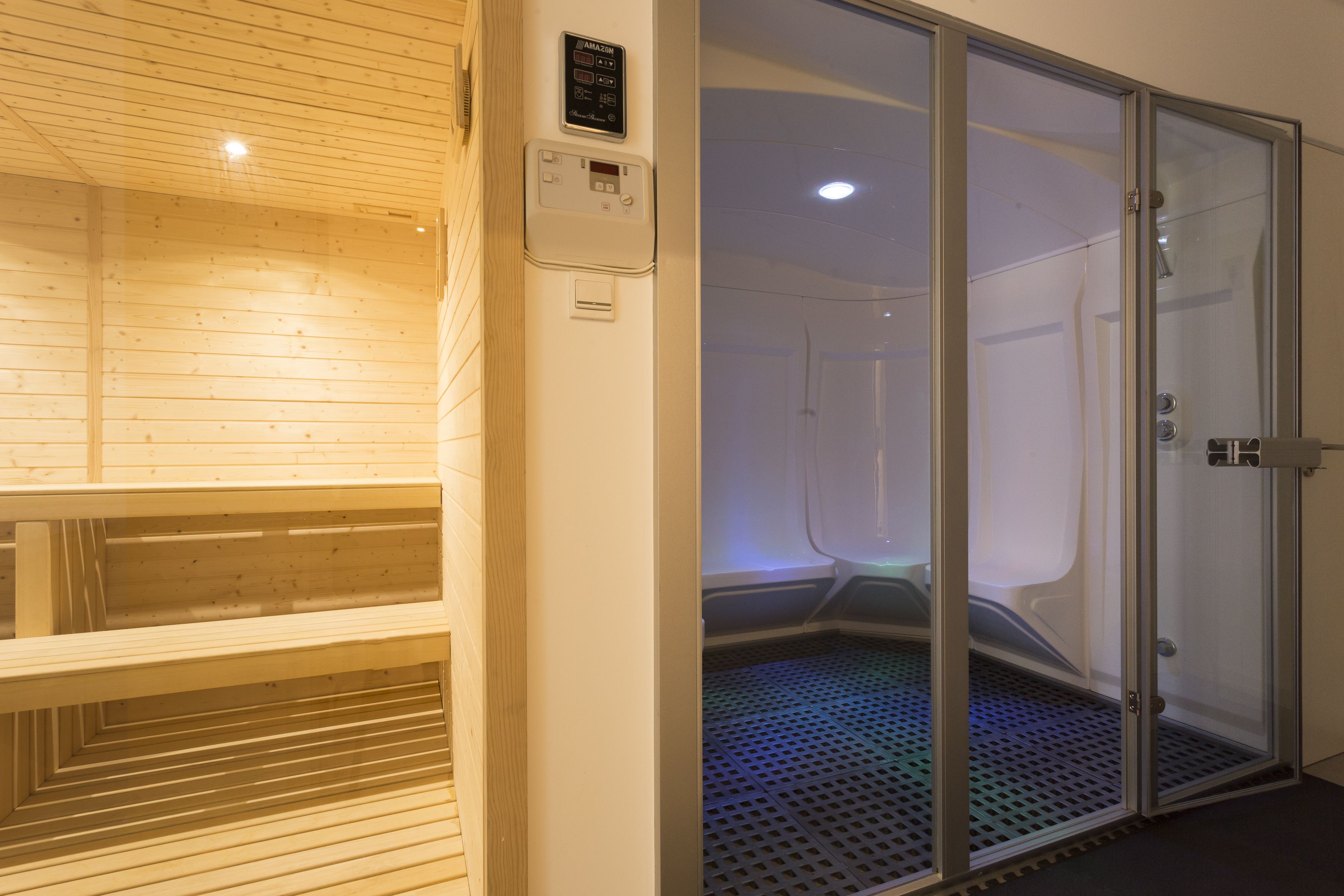 A sauna room with a wooden bench and a glass door leading to a steam room.