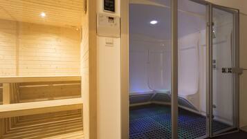 A sauna room with a wooden bench and a glass door leading to a steam room.