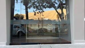 The entrance to El Huacachino Hotel with a glass door reflecting trees and a desert landscape.