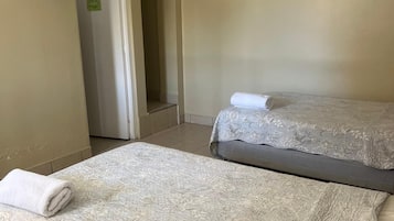 A hotel room with two beds, a flat-screen TV mounted on the wall, and a door leading to a hallway.
