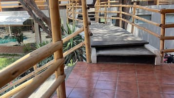 Una escalera de madera conduce a un espacio cubierto con una piscina al fondo.