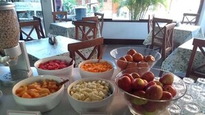 A breakfast buffet with various fruits and a coffee machine.