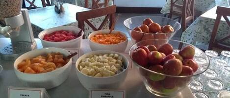 A breakfast buffet with various fruits and a coffee machine.
