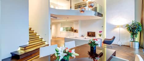 A modern interior with a dining area, a staircase, and a kitchen.