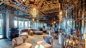 Ein stilvoller Lounge-Bereich mit Sofas und runden Tischen, großen Fenstern und dekorativen Deckenverkleidungen.